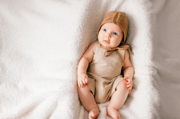 portret van bovenaf van mooie kleine baby in stijlvolle pyjama liggend op bed