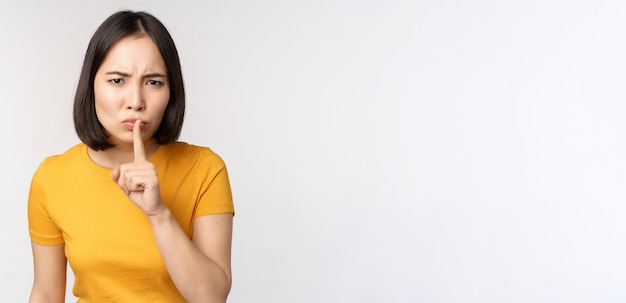 Portret van boze aziatische vrouw die de vinger naar de lippen duwt taboe stop met praten sig kijkt geërgerd s...