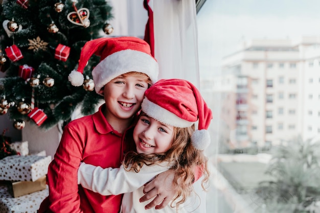 Portret van broers en zussen die kerstmanhoeden dragen en zich thuis omhelzen