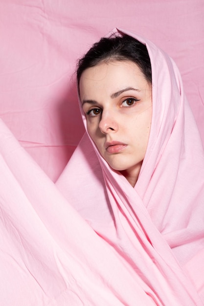 portret van brunette vrouw gewikkeld in roze doek roze achtergrond Hoge kwaliteit foto