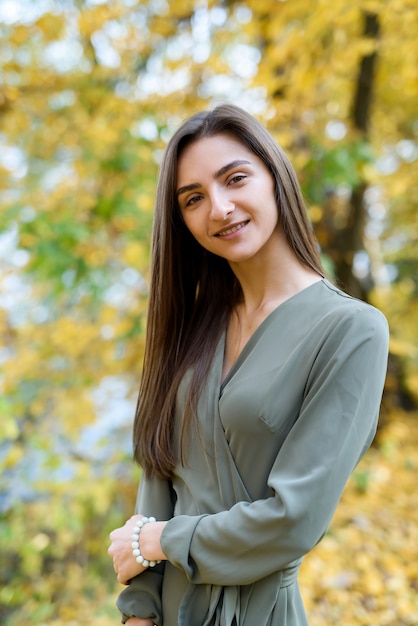 Portret van brunette vrouw in groene jurk poseren in herfst park