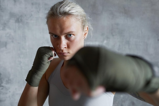 Foto portret van brutale professionele vrouwelijke bokser die jab punch doet en naar de camera kijkt