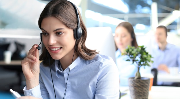 Portret van callcentermedewerker vergezeld door zijn team. Glimlachende klantenondersteuningsoperator op het werk.