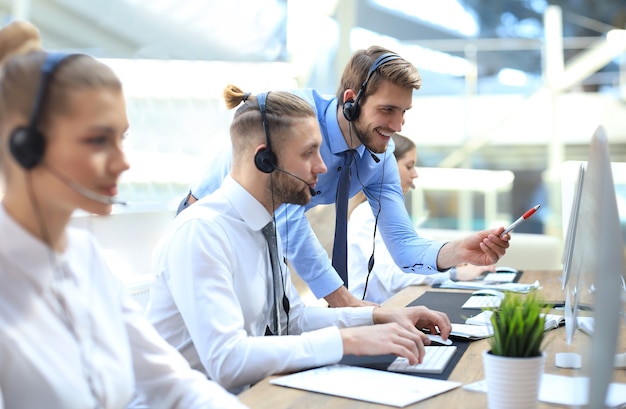 Portret van callcentermedewerker vergezeld door zijn team. Glimlachende klantenondersteuningsoperator op het werk.