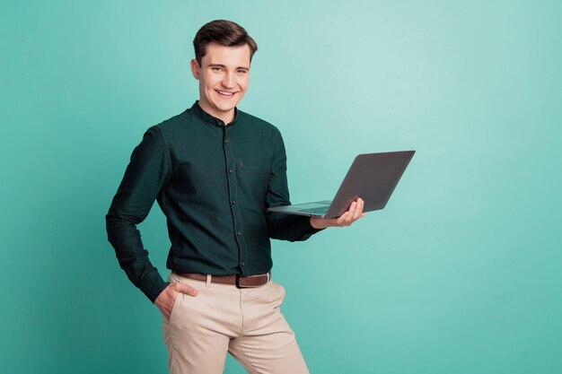 Portret van charmante aantrekkelijke vrolijke aardige man houdt netbook handzak op groenblauw achtergrond