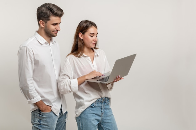 Portret van charmante geïnspireerde studenten die een laptop gebruiken die video's bekijkt die op een witte achtergrond zijn geïsoleerd