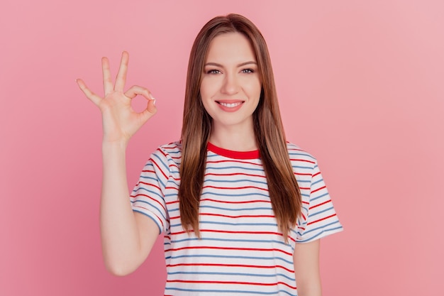 Portret van charmante, schattige promotor-damesvingers tonen een goed gebaar op een roze achtergrond