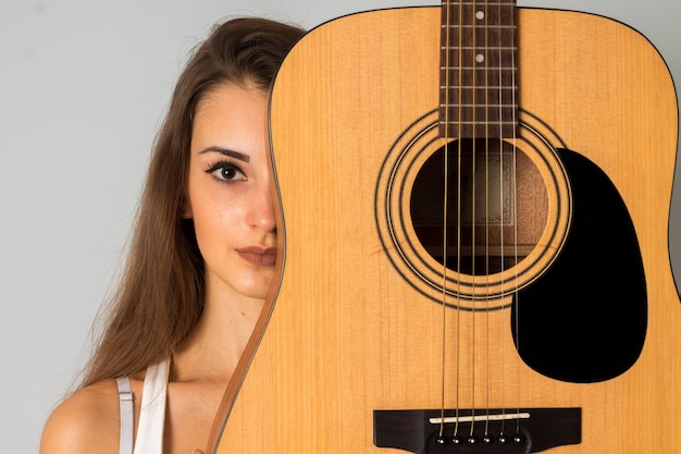 Portret van charmante vrouw met gitaar kijken naar de camera in studio