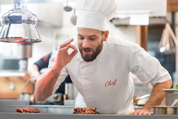 Portret van chef-kok in uniform met een heerlijk gerecht in de keuken van het restaurant