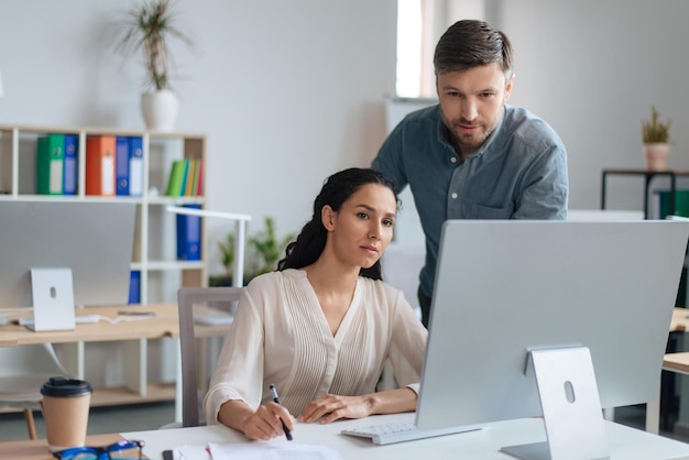 Portret van collega's die pc gebruiken en communiceren terwijl ze aan een zakelijk project werken en bespreken