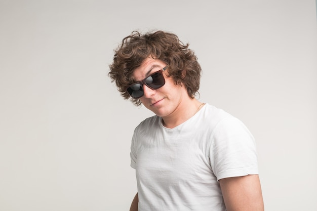 Portret van coole kerel in zonnebril in witte t-shirt op witte achtergrond