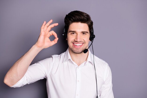 Portret van coole zelfverzekerde klantenservicemedewerker heeft hulplijn met klanten uitstekende feedback toon ok teken dragen headset formele slijtage kleding geïsoleerd over grijze kleur muur