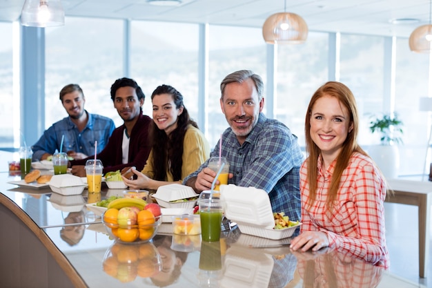 Portret van creatief commercieel team dat maaltijd in bureau heeft