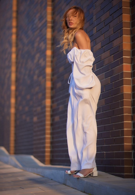 Portret van de achterkant van een elegant meisje met lang krullend haar dat op os loopt op de achtergrond van een oud gebouw