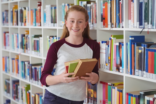 Portret van de gelukkige boeken van de schoolmeisjeholding in bibliotheek