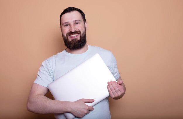 Foto portret van de glimlachende baarde mannelijke persoon met laptop in handen