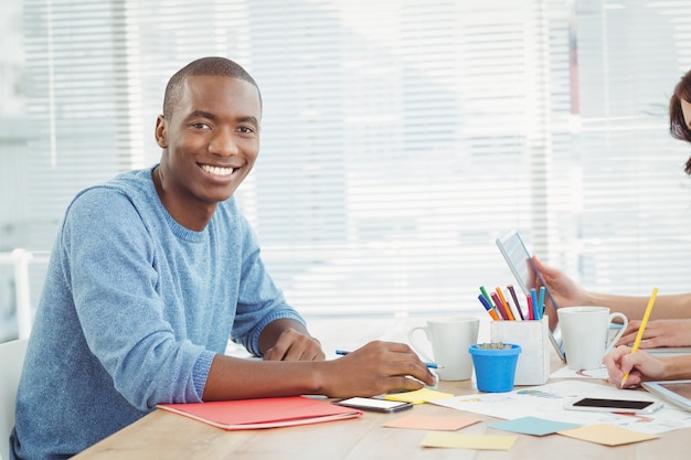 Portret van de glimlachende mens terwijl het werken bij bureau