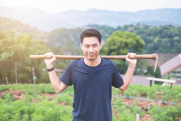 Portret van de Jonge Aziatische mens die in tuin werkt