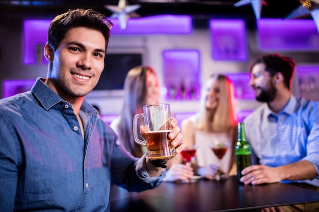 Portret van de jonge glimlachende mens die glas bier hebben bij barteller