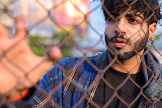 Portret van de jonge knappe bebaarde Indiase hipster man in de straten van de stad buitenshuis