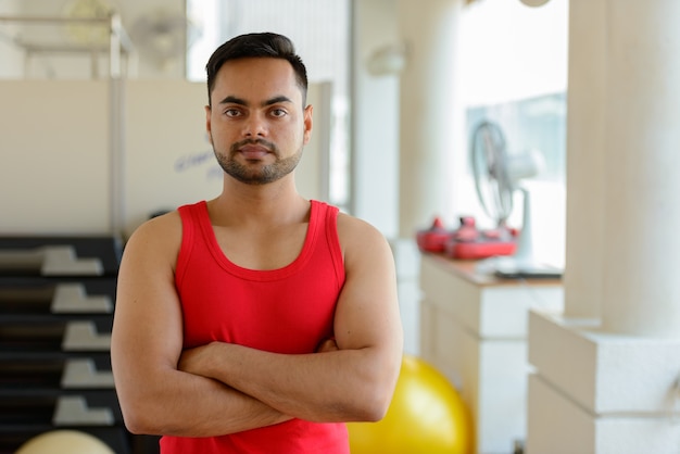 Portret van de jonge knappe bebaarde Indiase man trainen in de sportschool