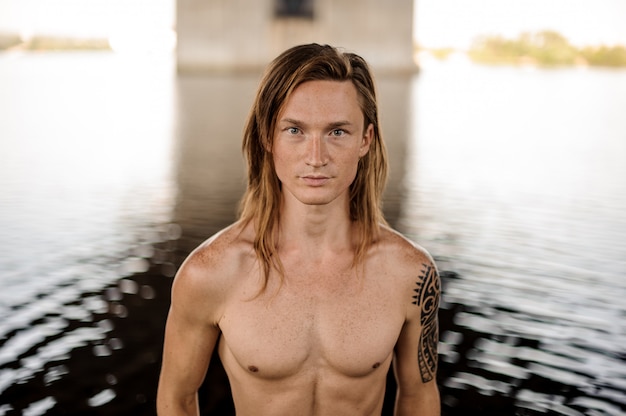 Portret van de jonge knappe lange en roodharige man die zich in water bevindt