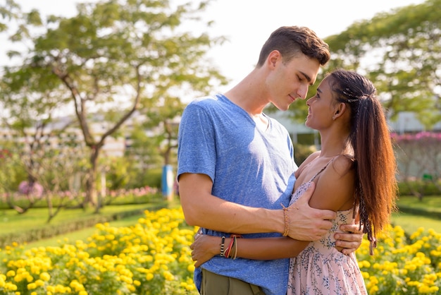 Portret van de jonge knappe man en de jonge mooie Aziatische vrouw die samen in het park ontspannen