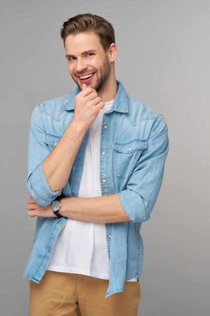 Portret van de jonge knappe man in jeansoverhemd over lichte muur