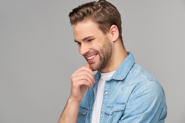 Portret van de jonge knappe man in jeansoverhemd over lichte muur