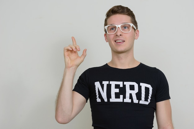 Foto portret van de jonge knappe nerdmens tegen witte muur