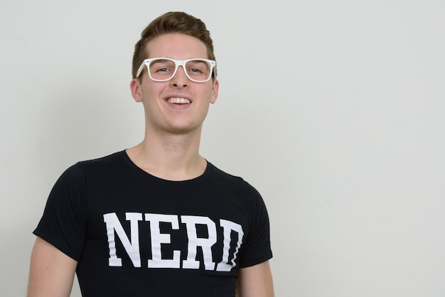 Portret van de jonge knappe nerdmens tegen witte muur