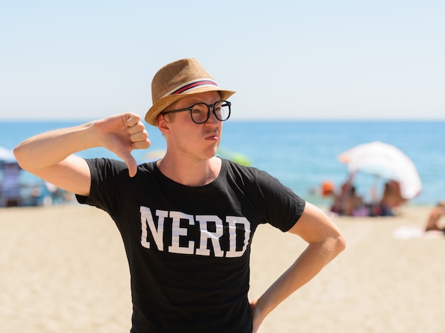 Portret van de jonge knappe toeristenmens als nerd op het strand in spanje