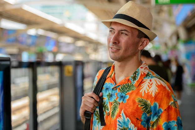 Portret van de jonge knappe toeristenmens bij skytrain-station in de stad