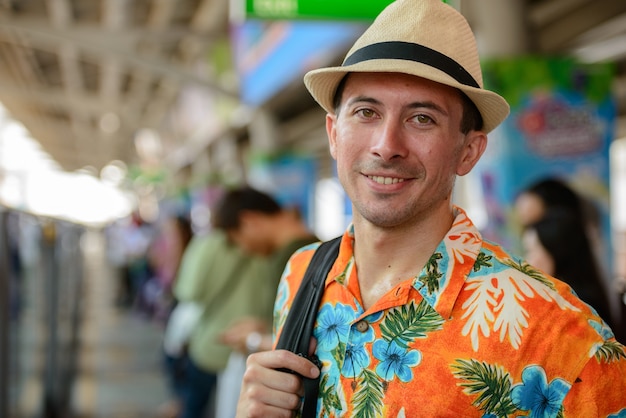 Foto portret van de jonge knappe toeristenmens bij skytrain-station in de stad