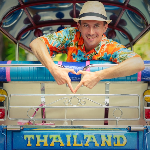 Foto portret van de jonge knappe toeristenmens die tuk tuk berijden als lokaal openbaar vervoer in de stad van bangkok