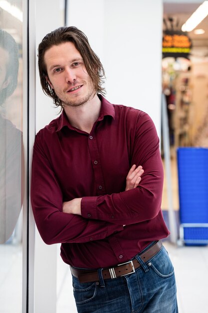 Portret van de mens die buiten de winkel leunt