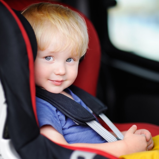 Portret van de mooie zitting van de peuterjongen in autozetel