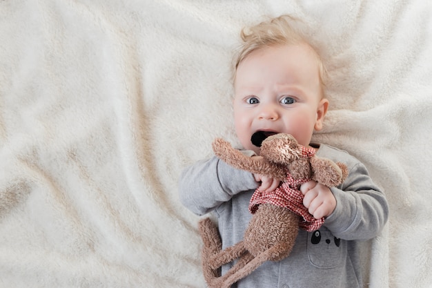 Portret van de oude babyjongen van vijf maanden met zacht stuk speelgoed op witte deken