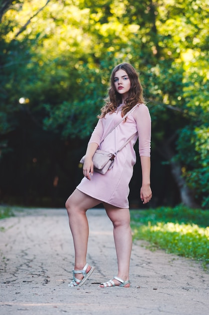 Portret van de volledige lengte van een mooie plus size fashion model in roze jurk jonge vrouw buiten in de natuur