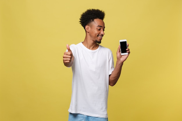 Portret van de vrolijke Afrikaanse Amerikaanse mens die op cellphone met duimen op handteken spreekt