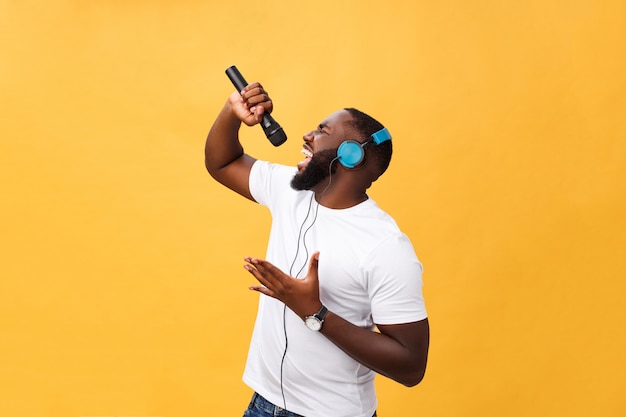 Portret van de vrolijke positieve elegante knappe afrikaanse microfoon van de mensenholding en het hebben van hoofdtelefoons