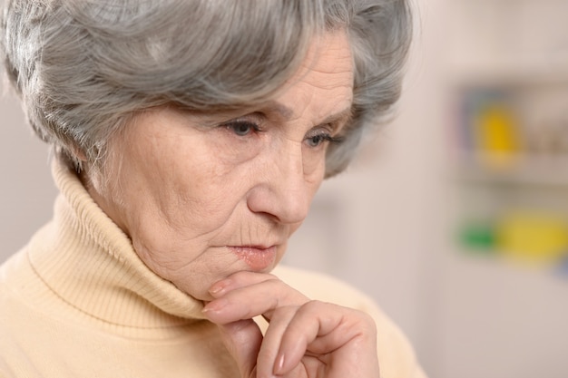 Portret van denkende oudere vrouw thuis