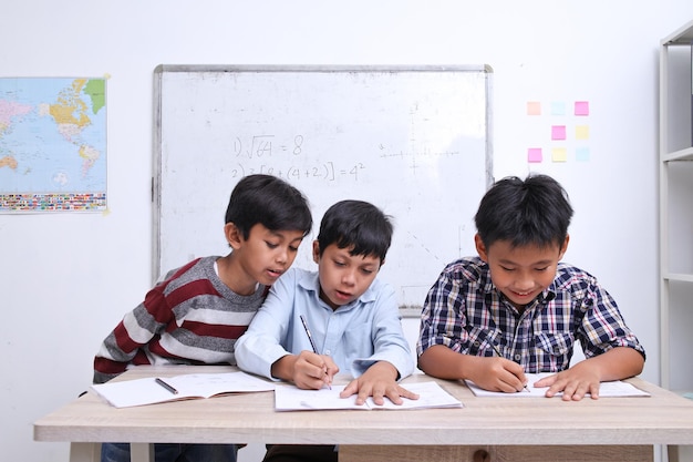 Portret van diverse schooljongen die samen studeren in de klas en wiskunde leren schrijven op boeken