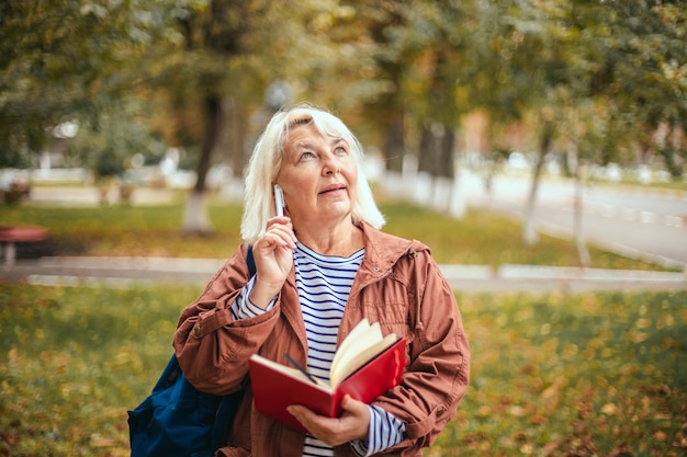Portret van doordachte geconcentreerde senior vrouw met blocnote en pen