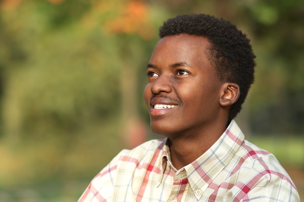 Portret van doordachte peinzende jonge gelukkig zwarte Afro-Amerikaanse man in het park