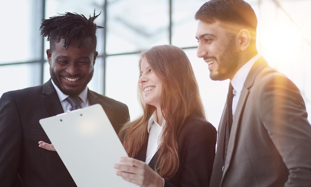 Portret van drie mensen in zakelijke kleding die een document bespreken in het kantoor