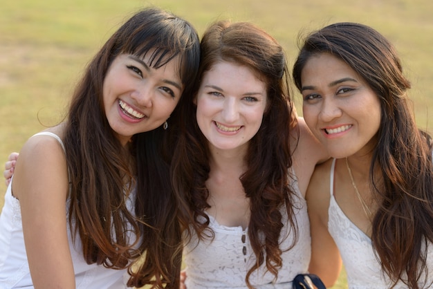 Portret van drie multi-etnische jonge mooie vrouwen als vrienden samen in het park buiten