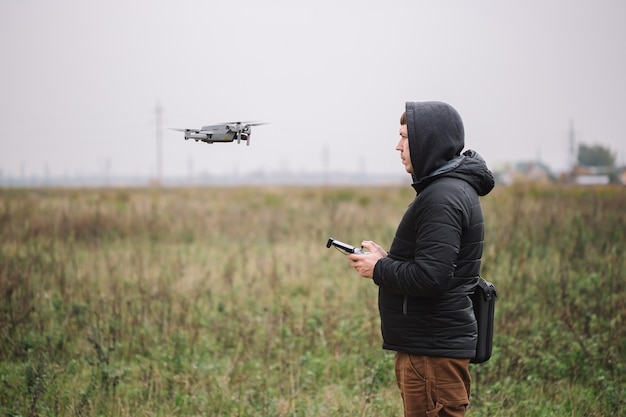 Portret van drone-operator vliegende vliegtuigen quadcopter in de buurt van het bos. Technische details met drone en afstandsbediening