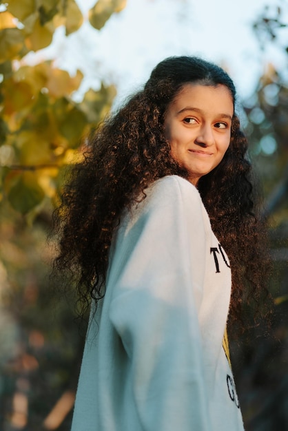 Foto portret van een 13-jarig meisje vol emoties dat glimlacht en naar de zonsondergang kijkt door de zonnestralen.