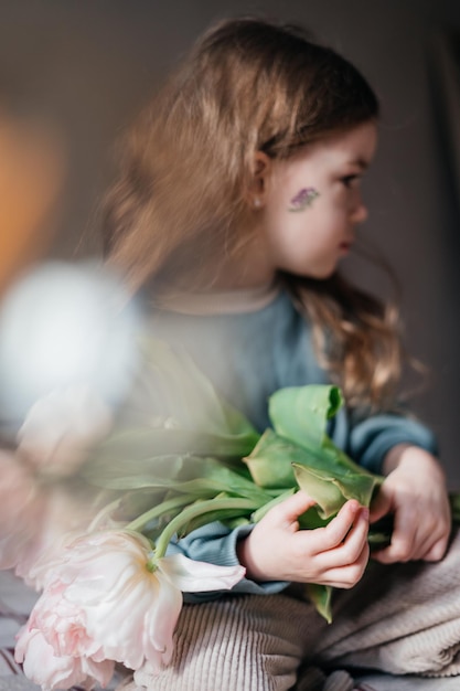 Portret van een 4-jarig meisje met een boeket verse roze tulpen poserend voor een foto met ochtendlicht